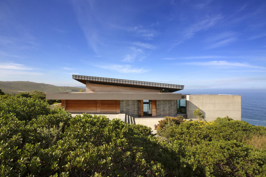 An elevated look at the home showcases the wood and stone structure settling into the landscape seamlessly. An elevated look at the home showcases the wood and stone structure settling into the landscape seamlessly.