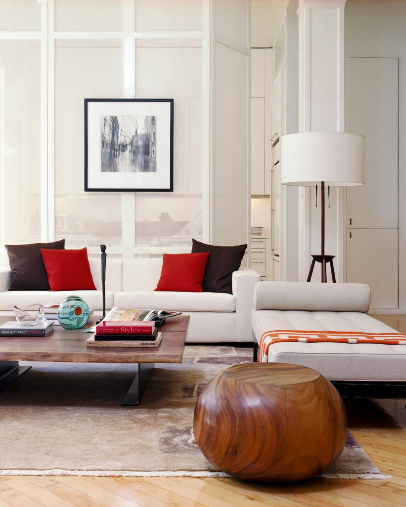 The open design space holds an array of unique furniture pieces, including this solid wood spherical ottoman and large natural wood coffee table, standing with off white sofa and chaise lounge over the hardwood flooring. The open design space holds an array of unique furniture pieces, including this solid wood spherical ottoman and large natural wood coffee table, standing with off white sofa and chaise lounge over the hardwood flooring.