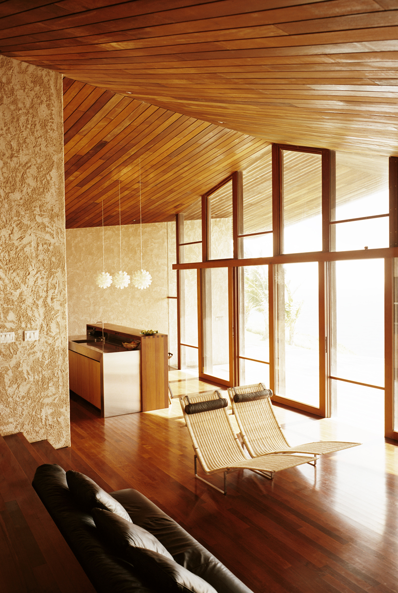 Glancing over the stair-built sofa, the kitchen area is visible, defined by a large two-tier island. The vaulted hardwood ceiling reaches a peak here, marking the center of the home. Glancing over the stair-built sofa, the kitchen area is visible, defined by a large two-tier island. The vaulted hardwood ceiling reaches a peak here, marking the center of the home.