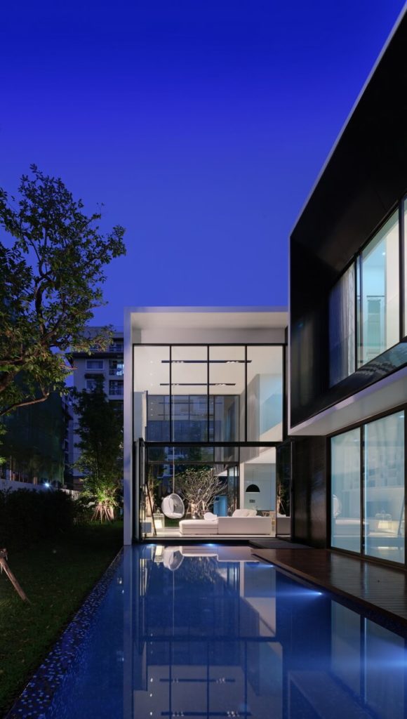 The lengthy pool sits below a hardwood patio stretch, with lush yard bracketing it on the left. The interior of the home is alight over the water. The lengthy pool sits below a hardwood patio stretch, with lush yard bracketing it on the left. The interior of the home is alight over the water.