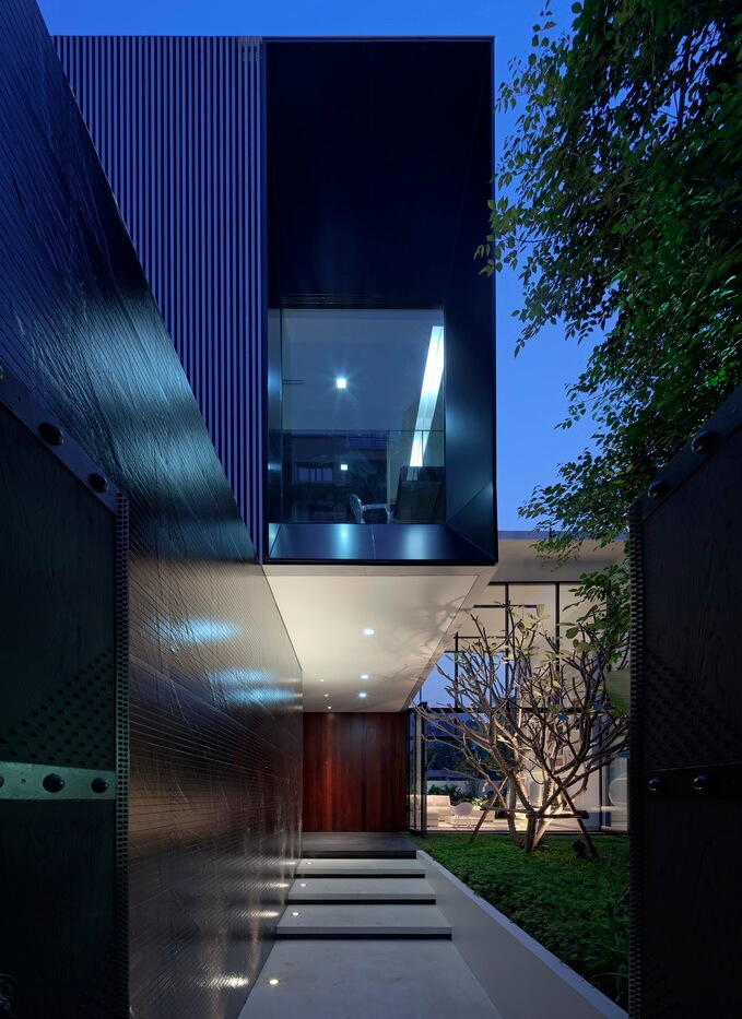 Walking up the main entryway, the dark walls give way to the metallic box structure above. Rich wood paneling surrounds the entrance at center. Walking up the main entryway, the dark walls give way to the metallic box structure above. Rich wood paneling surrounds the entrance at center.
