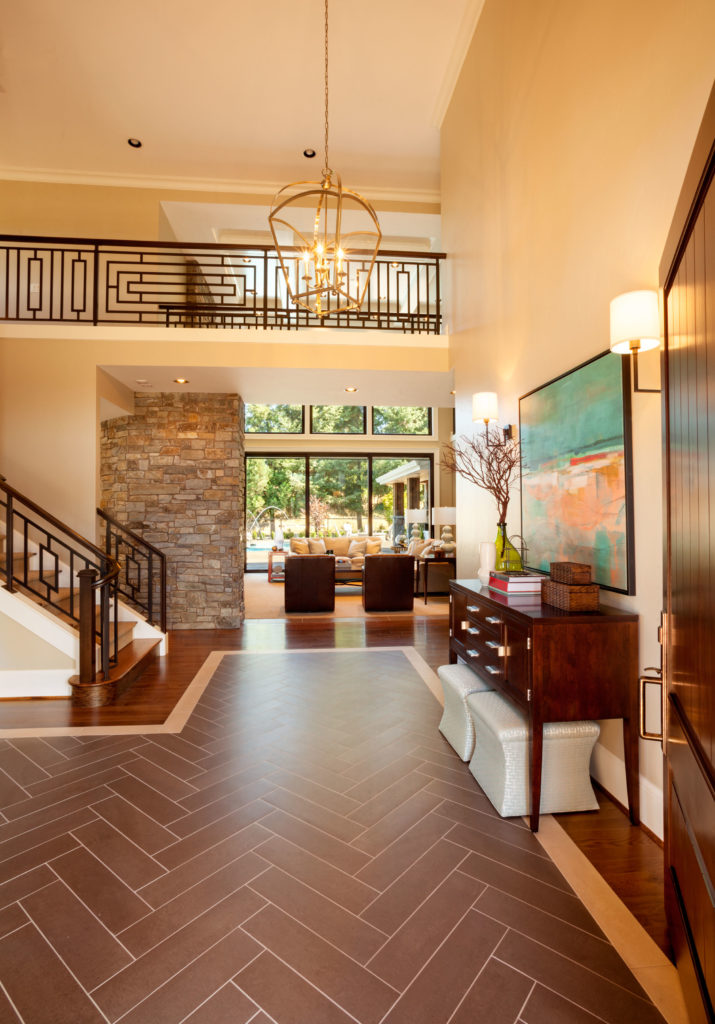 Although they aren't visible in this picture, a ton of natural light filters through oversized windows in the two-story foyer. The herringbone pattern of the polished tile floor is outlined by a light wood before turning into a rich dark wood that matches the staircase and furniture. Although they aren't visible in this picture, a ton of natural light filters through oversized windows in the two-story foyer. The herringbone pattern of the polished tile floor is outlined by a light wood before turning into a rich dark wood that matches the staircase and furniture.