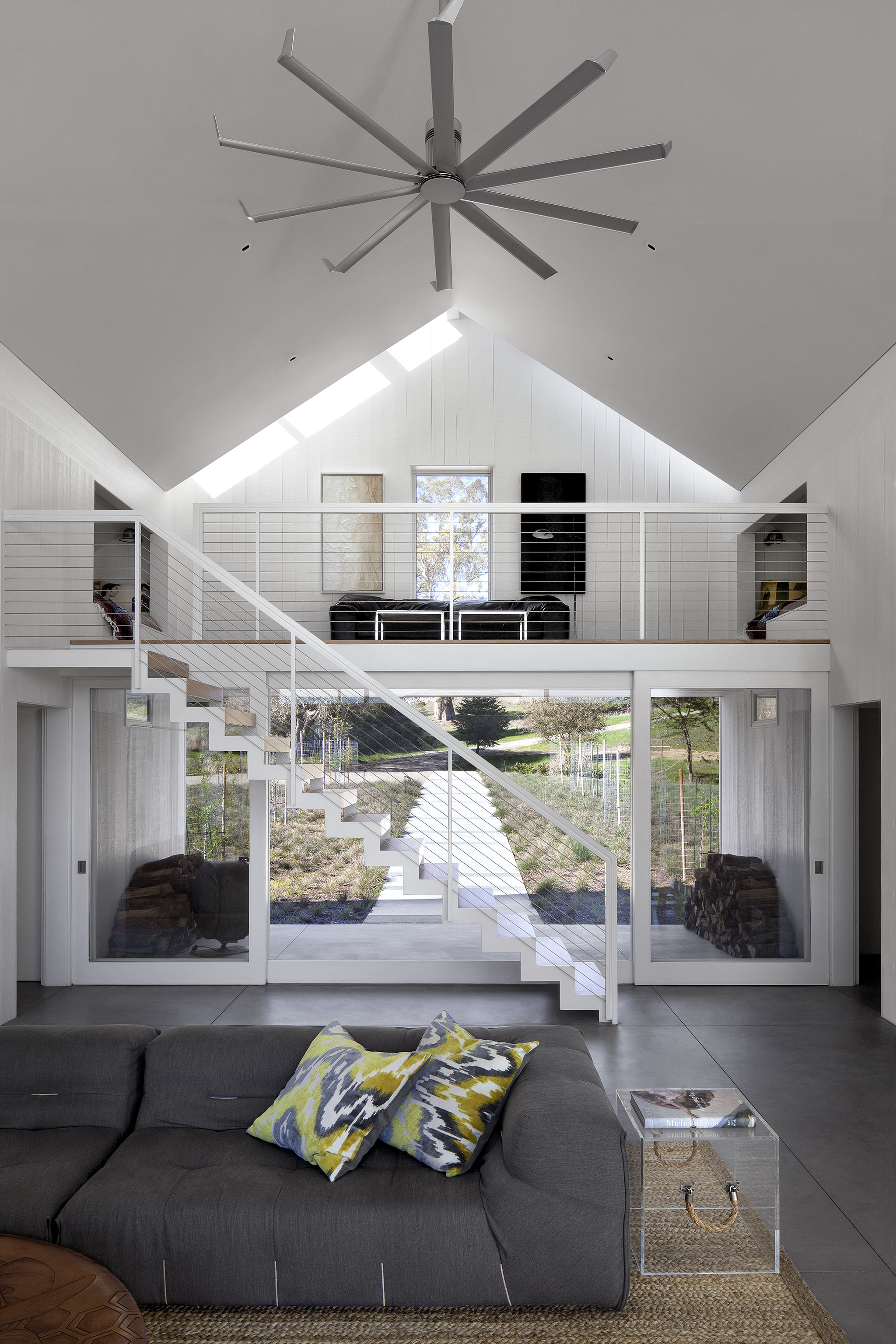 The two-story living room also holds this loft area above the doorway, with subtle skylights framed against the roof edge. A massive aluminum ceiling fan efficiently circulates air in the large space. The two-story living room also holds this loft area above the doorway, with subtle skylights framed against the roof edge. A massive aluminum ceiling fan efficiently circulates air in the large space.