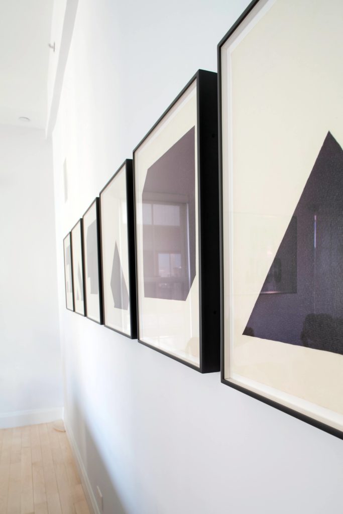The series of minimalist pieces on the living room wall are framed in dark wood, adding detail and contrast to the white space. The series of minimalist pieces on the living room wall are framed in dark wood, adding detail and contrast to the white space.