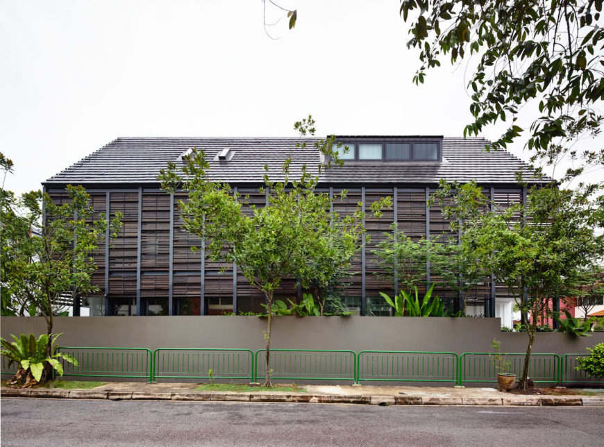 A view from across the street at the home, showing the extent of the privacy screen. The lower half of the home is not covered by the screen, because the concrete fence and lush landscaping provide their own screening effect. A view from across the street at the home, showing the extent of the privacy screen. The lower half of the home is not covered by the screen, because the concrete fence and lush landscaping provide their own screening effect.