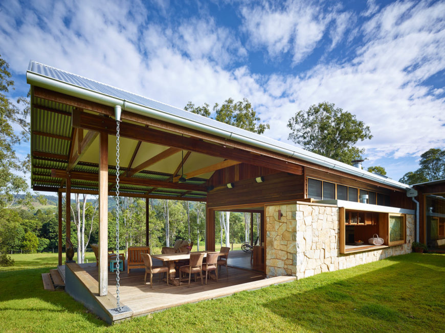 Seen from the rear, we witness the expansive veranda, replete with hardwood flooring and an extensive set of dining and relaxing furniture. The large sliding window to the right opens the kitchen to the outdoors. Seen from the rear, we witness the expansive veranda, replete with hardwood flooring and an extensive set of dining and relaxing furniture. The large sliding window to the right opens the kitchen to the outdoors.