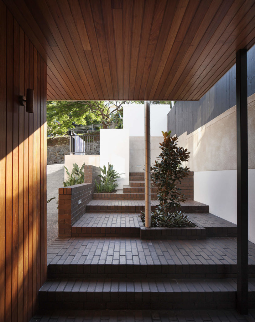Here's a glimpse out the front of the home, showing the immense sense of privacy and coziness granted by the home's placement in the landscape. Concrete, brick, and rich wood panels create a timeless mixture. Here's a glimpse out the front of the home, showing the immense sense of privacy and coziness granted by the home's placement in the landscape. Concrete, brick, and rich wood panels create a timeless mixture.