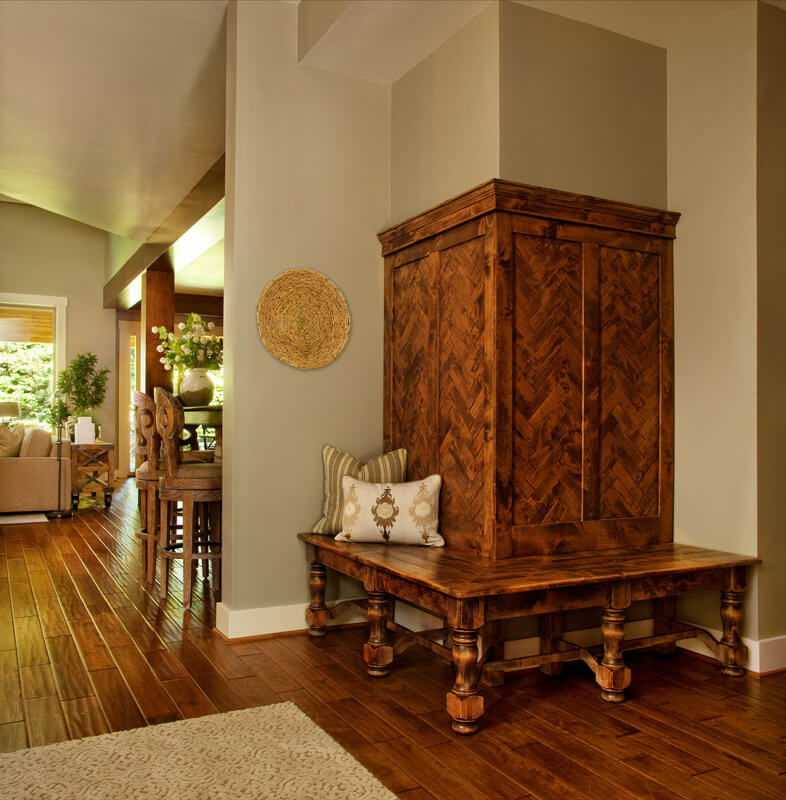Over the rich natural hardwood flooring stands a variety of intricately carved wood furniture pieces, including this wraparound bench feature, built into a corner wall. Over the rich natural hardwood flooring stands a variety of intricately carved wood furniture pieces, including this wraparound bench feature, built into a corner wall.