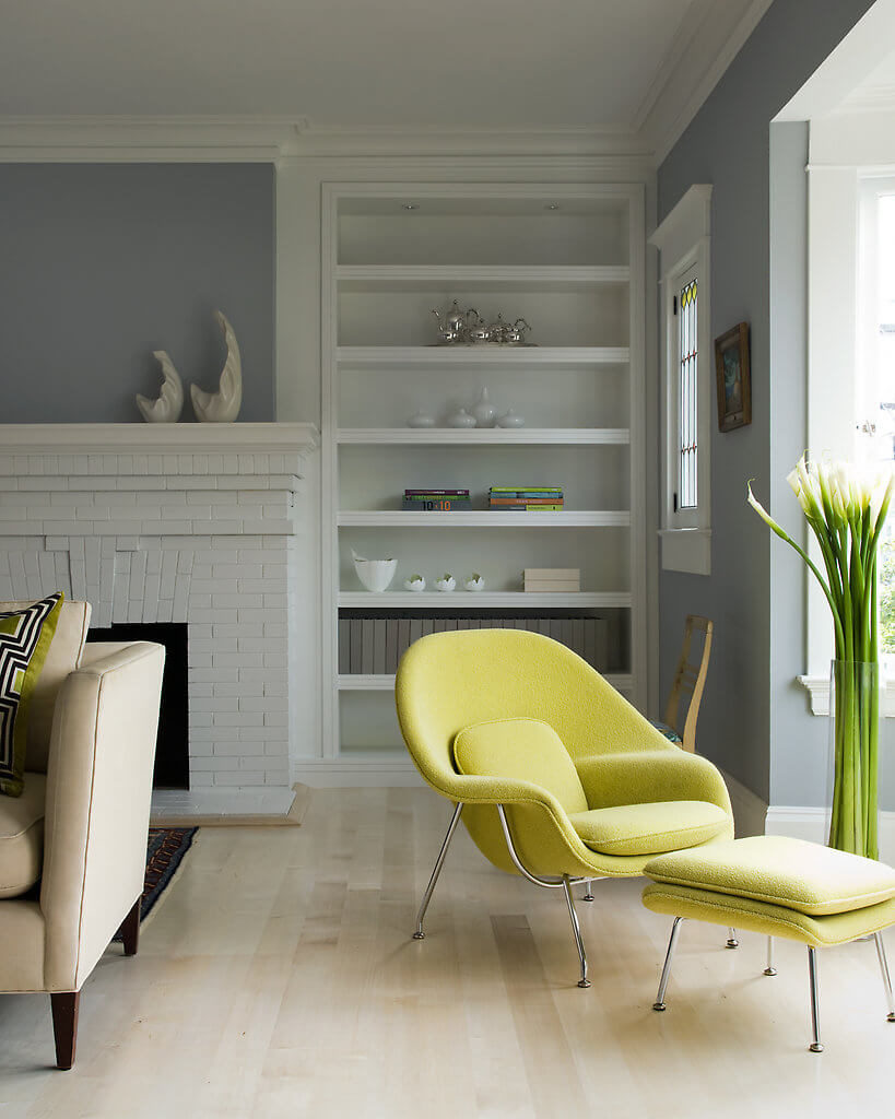 The elegant curves of this green-yellow armchair adds to the modernized retro feel of the home and pair perfectly with the standing floral arrangement. The original fireplace remains in place, but is given a new look with a touch of white paint. The elegant curves of this green-yellow armchair adds to the modernized retro feel of the home and pair perfectly with the standing floral arrangement. The original fireplace remains in place, but is given a new look with a touch of white paint.