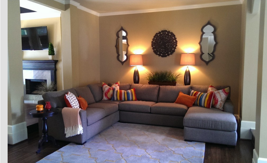 The cozy family room is anchored by this large L-shaped sectional with chaise lounge, standing beneath a set of mirrors and carved wood wall decorations. The living room can be seen at left, with the marble wrapped fireplace standing below a wall mounted television. The cozy family room is anchored by this large L-shaped sectional with chaise lounge, standing beneath a set of mirrors and carved wood wall decorations. The living room can be seen at left, with the marble wrapped fireplace standing below a wall mounted television.