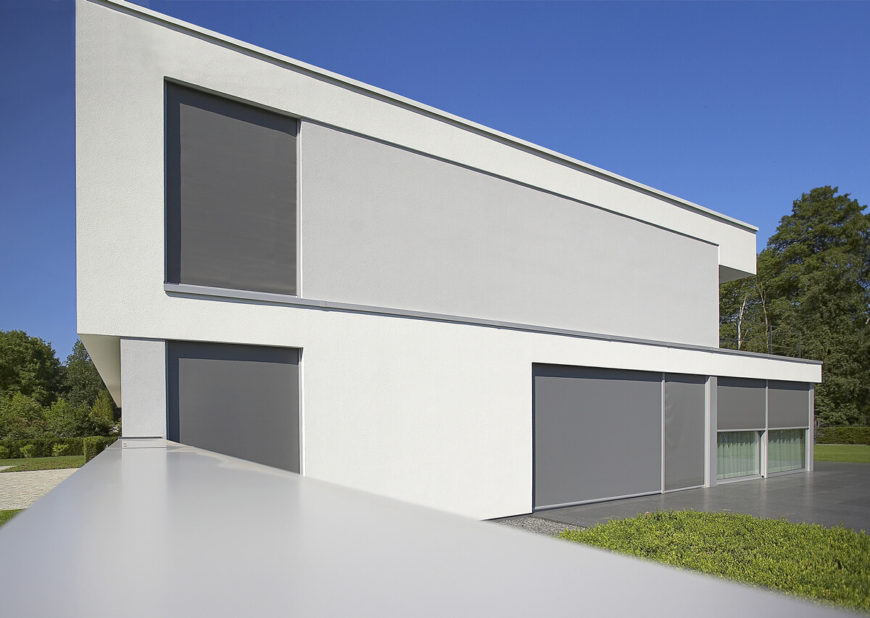 With shades drawn during the brightest part of day, the home becomes an almost monolithic slab of white and grey, concealing the intricate detail within and standing cleanly apart from the surrounding forested landscape. With shades drawn during the brightest part of day, the home becomes an almost monolithic slab of white and grey, concealing the intricate detail within and standing cleanly apart from the surrounding forested landscape.