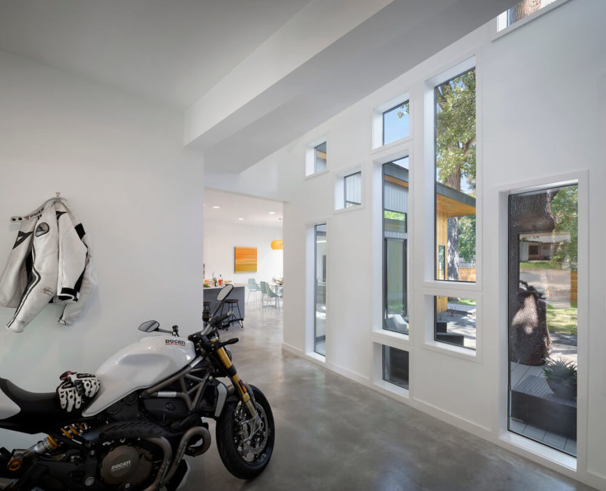On the other side of the multi-windowed wall we see a transitional space leading from the main entry into the open-plan kitchen and dining area. The innovative window sets allow for a blurred line between indoors and out. On the other side of the multi-windowed wall we see a transitional space leading from the main entry into the open-plan kitchen and dining area. The innovative window sets allow for a blurred line between indoors and out.