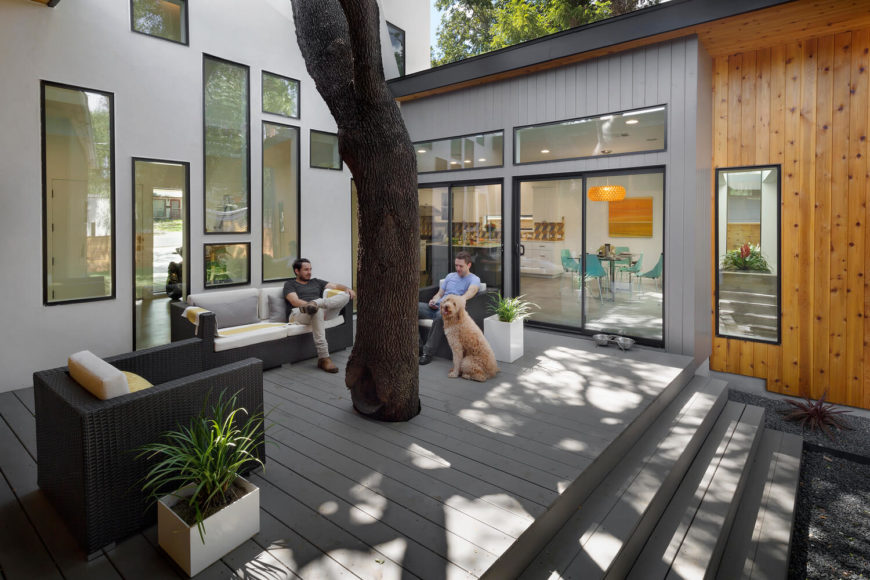 Here we see the preserved oak at the center of the property, wrapped in light grey patio decking and surrounded by various sized windows. A set of rattan deck furniture allows for nature centric gatherings. Here we see the preserved oak at the center of the property, wrapped in light grey patio decking and surrounded by various sized windows. A set of rattan deck furniture allows for nature centric gatherings.