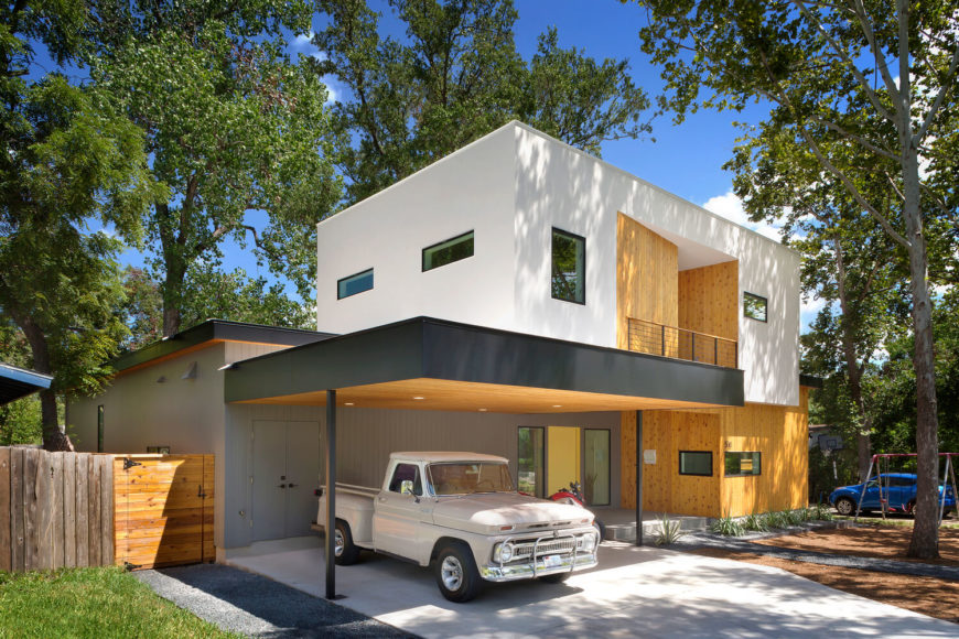 The standout white box design, floating over natural wood paneling, makes for an imposing presence when seen from the street. A lengthy overhang protects a parking space, encompassing the grand entry as well. The standout white box design, floating over natural wood paneling, makes for an imposing presence when seen from the street. A lengthy overhang protects a parking space, encompassing the grand entry as well.