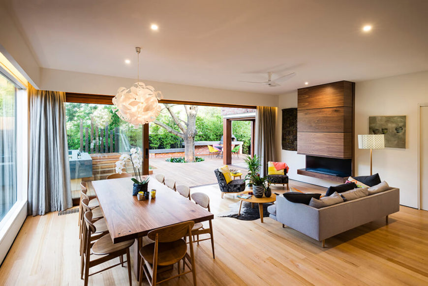 Moving into the home itself, we see the open plan living room basking in the splendor of natural sunlight, through massive sliding glass panels. The interior balances white walls against rich natural wood throughout. Moving into the home itself, we see the open plan living room basking in the splendor of natural sunlight, through massive sliding glass panels. The interior balances white walls against rich natural wood throughout.