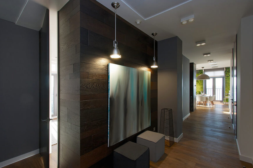 Entry to the home is marked by a beautiful wooden accent wall with two pendant lights and a large gradient painting. Beneath the painting are two minimalistic cube seats. Small ceiling lights are arranged flush with the ceiling and light the length of the hallway, which provides access to all of the bedrooms and bathrooms. Entry to the home is marked by a beautiful wooden accent wall with two pendant lights and a large gradient painting. Beneath the painting are two minimalistic cube seats. Small ceiling lights are arranged flush with the ceiling and light the length of the hallway, which provides access to all of the bedrooms and bathrooms.