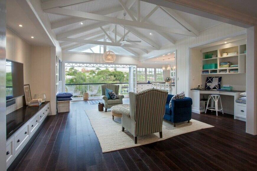 This open plan living room sports a high contrast look with dark hardwood flooring and white walls and ceiling. The vaulted ceiling is crossed with white exposed beams for a truly unified look.