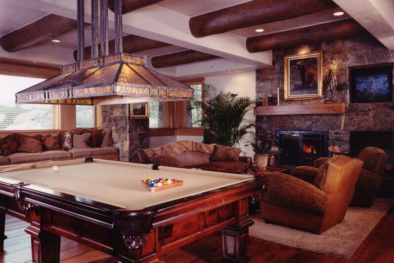 The rich stone walls and hardwood flooring conspire within this living room for an elegant, timeless look. Log style exposed beams cross the white ceiling for high contrast.
