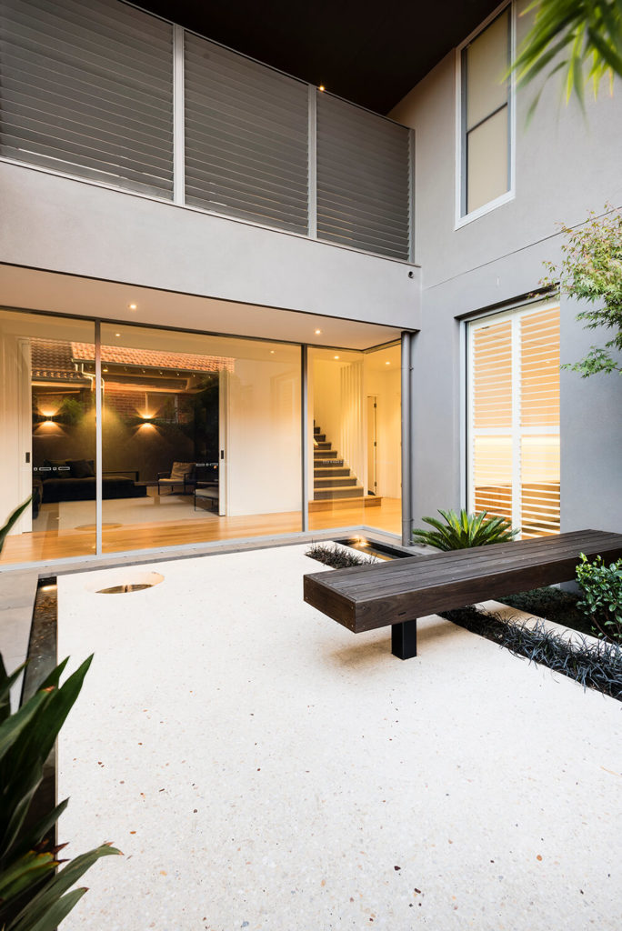 The northern courtyard features a low pond that flows into a border around the space. Another alpine white concrete slab appears to float over the pond. Dwarf papyrus springs up from the center of the pond and the surrounding plants reinforce the Asiatic themes throughout the garden. The timber bench, pictured here, hangs off the house and crosses a strip bed filled with liriopes. The northern courtyard features a low pond that flows into a border around the space. Another alpine white concrete slab appears to float over the pond. Dwarf papyrus springs up from the center of the pond and the surrounding plants reinforce the Asiatic themes throughout the garden. The timber bench, pictured here, hangs off the house and crosses a strip bed filled with liriopes.