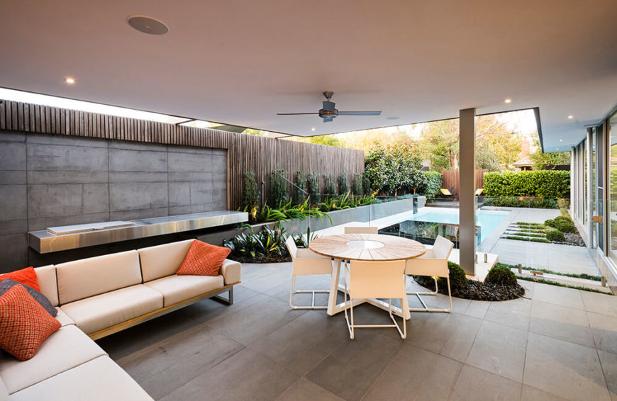 back patio, or alfresco area, features a sitting and dining area. Along the concrete wall is a stainless steel bar with an integrated Electrolux grill. A glass fence separates the alfresco area from the pool area of the backyard. back patio, or alfresco area, features a sitting and dining area. Along the concrete wall is a stainless steel bar with an integrated Electrolux grill. A glass fence separates the alfresco area from the pool area of the backyard.