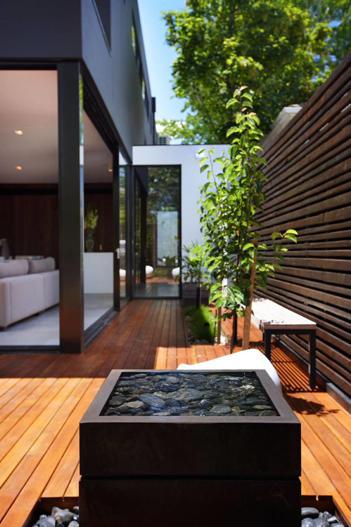 Here's a close look at the unique cubic water feature, filled with polished stones and spilling into a wraparound bed of stones. Down the length of the patio we can see into the interior of the home via large expanses of glass. Here's a close look at the unique cubic water feature, filled with polished stones and spilling into a wraparound bed of stones. Down the length of the patio we can see into the interior of the home via large expanses of glass.