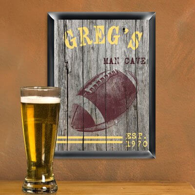 We love the idea of hanging up cheeky "man cave" signs in the man cave, a knowing wink to the boys' room history of the space. It's always great when wall decorations combine a couple passions. In this case, we see a football themed sign done up in antique textures for a rustic, old fashioned appearance. This one can be personalized with up to 15 characters at the top and 30 characters below. We love the idea of hanging up cheeky "man cave" signs in the man cave, a knowing wink to the boys' room history of the space. It's always great when wall decorations combine a couple passions. In this case, we see a football themed sign done up in antique textures for a rustic, old fashioned appearance. This one can be personalized with up to 15 characters at the top and 30 characters below.