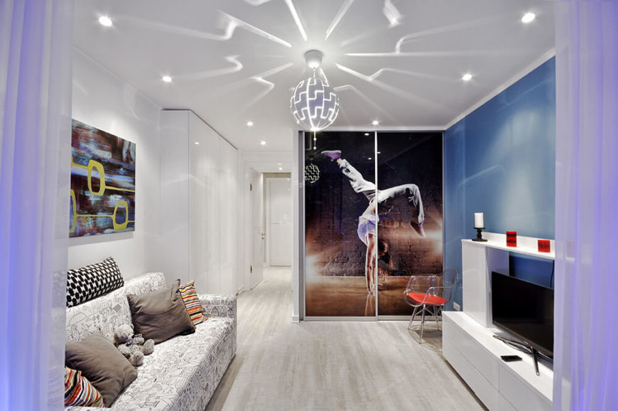 Here's a look at the master bedroom sitting area, with the dressing room in the background. A sliding door entry is obscured by a large photo print. The disco-styled overhead light casts patterns over the white and blue space. Here's a look at the master bedroom sitting area, with the dressing room in the background. A sliding door entry is obscured by a large photo print. The disco-styled overhead light casts patterns over the white and blue space.