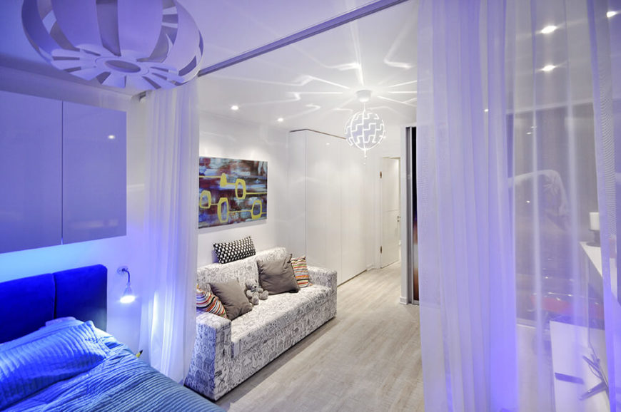 Moving further into the room, we see the bed partitioned by a full size curtain. The soft blue glow of the lighting is meant to further clarify this space as distinct. Moving further into the room, we see the bed partitioned by a full size curtain. The soft blue glow of the lighting is meant to further clarify this space as distinct.