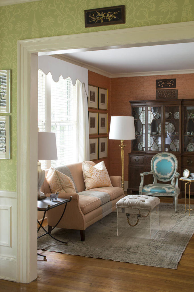 Pulling back from the living room into the foyer, we see that the space is absolutely flush with intriguing hybrid style details, like the button tufted ottoman crafted over an acrylic cube. The hardwood flooring anchors everything in a traditional tone. Pulling back from the living room into the foyer, we see that the space is absolutely flush with intriguing hybrid style details, like the button tufted ottoman crafted over an acrylic cube. The hardwood flooring anchors everything in a traditional tone.