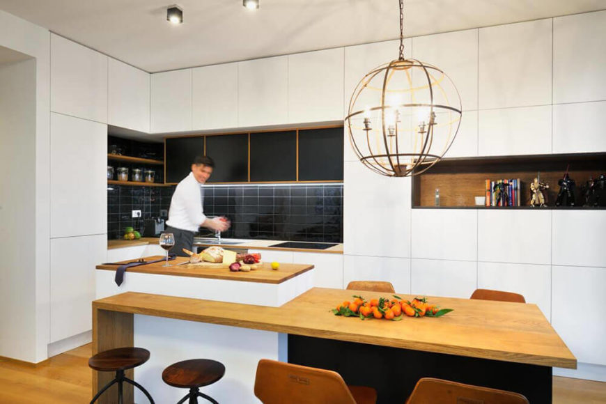 The kitchen boasts deep black subway tile backsplash as well as a rich natural wood shelf built into the wall. Touches like these add contrast and nuance to the modern space. The kitchen boasts deep black subway tile backsplash as well as a rich natural wood shelf built into the wall. Touches like these add contrast and nuance to the modern space.