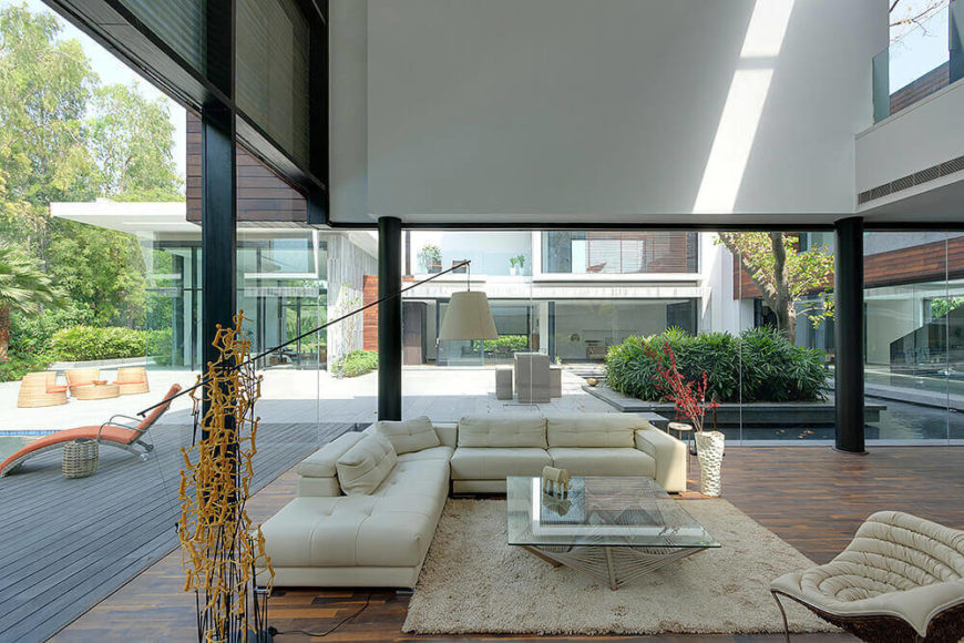 Now inside the home, we see the expansive views afforded within the living room, with glass wrapping entirely around. The courtyard can be seen clearly across the hardwood flooring. Now inside the home, we see the expansive views afforded within the living room, with glass wrapping entirely around. The courtyard can be seen clearly across the hardwood flooring.