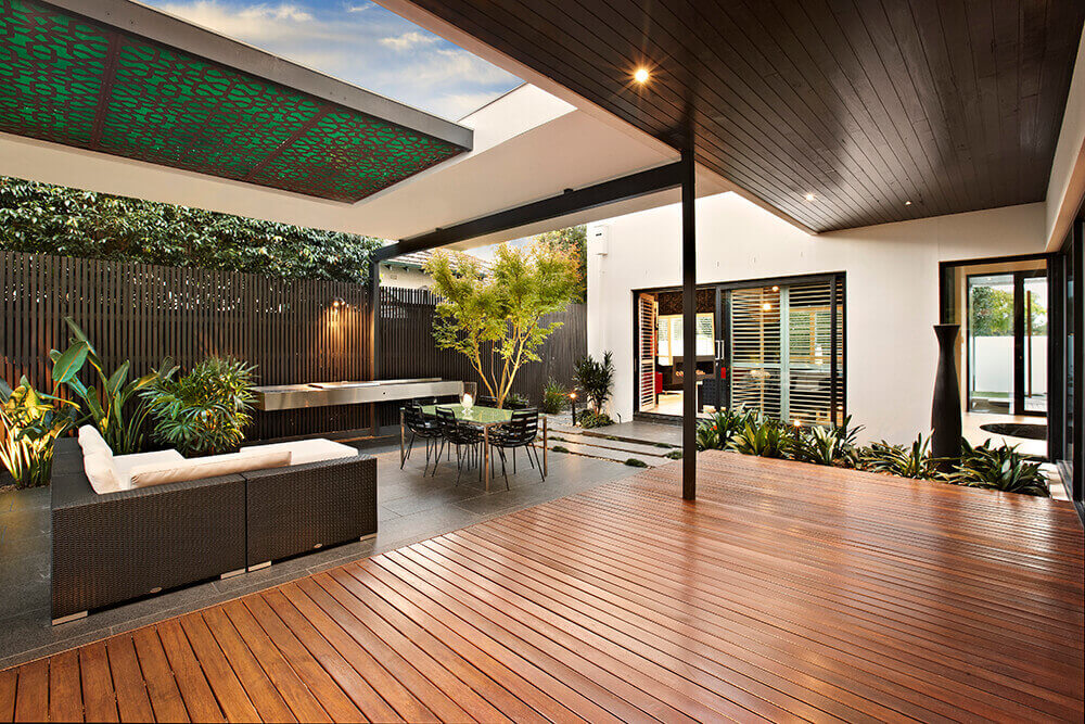 This home features a modish outdoor kitchen with a floating vanity counter, small dining table set and a patio area.
