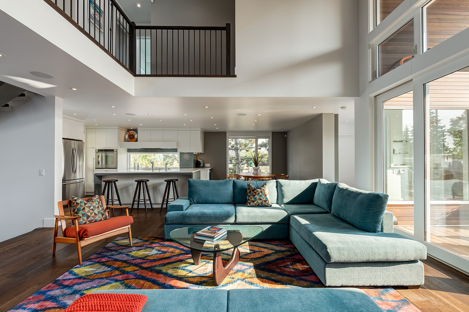 The central living space extends all the way up to the second floor with wooden railings taking a peek over the picture. The central living space extends all the way up to the second floor with wooden railings taking a peek over the picture.