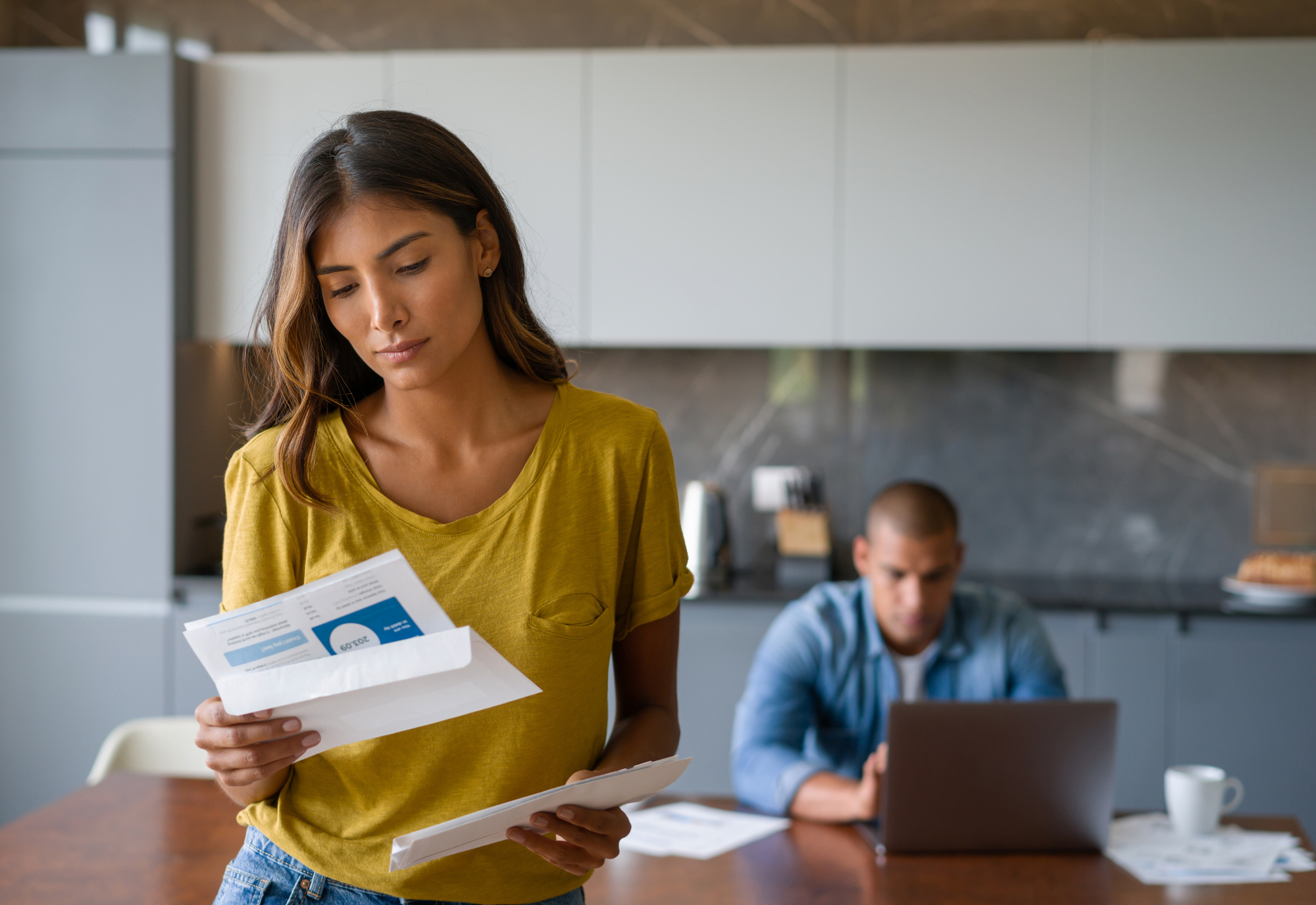 woman reading letter confused, man working on computer