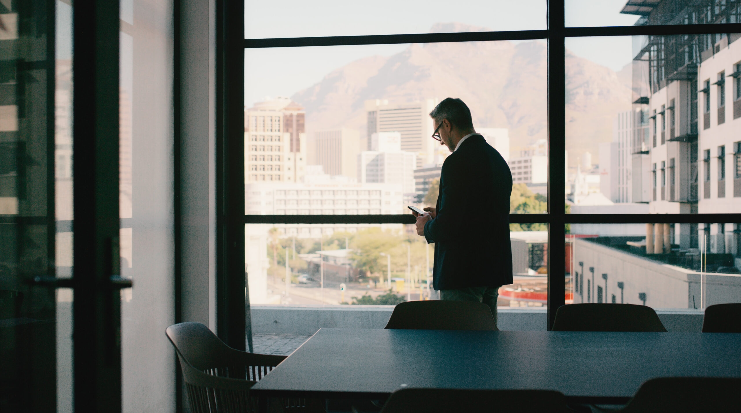 Office, window and businessman with phone for notification, reading email and chat to contact. Law firm, mature person or lawyer with mobile for justice, text or information for case update to client