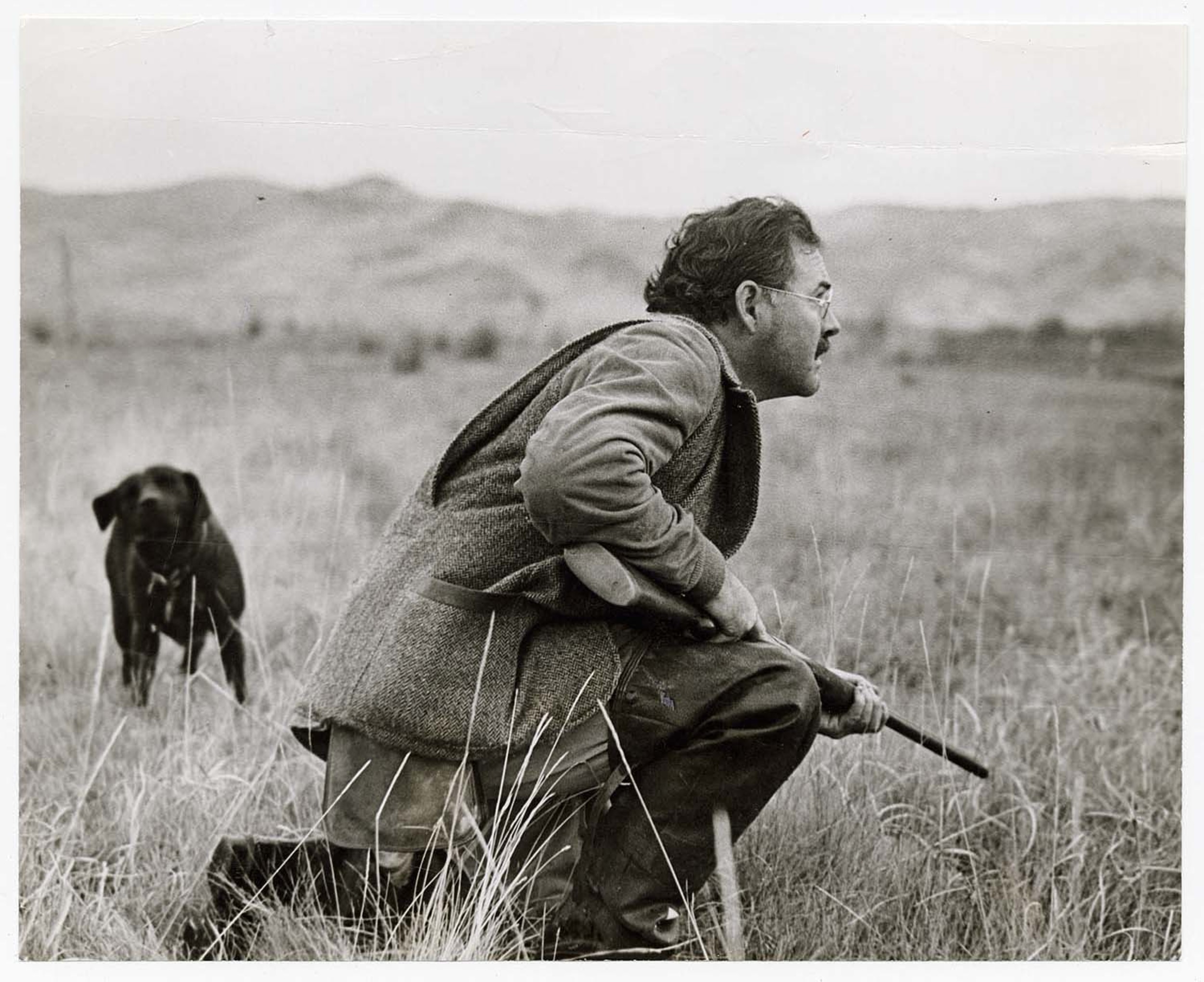 [Ernest Hemingway crouching with rifle, Sun Valley, Idaho