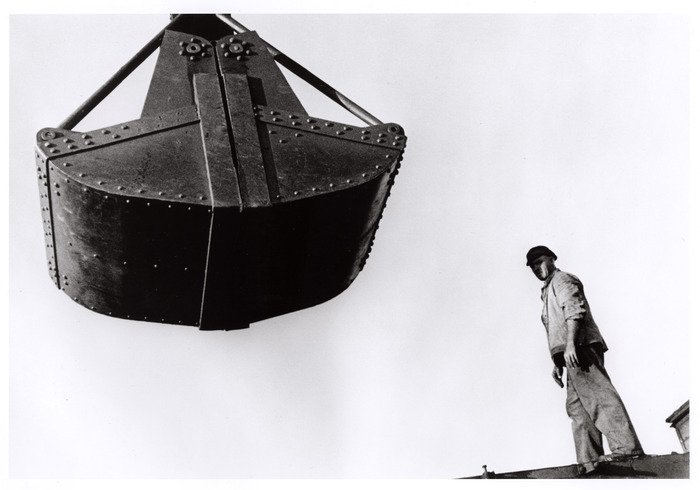 [Man and hanging piece of machinery, Saarland, France]
