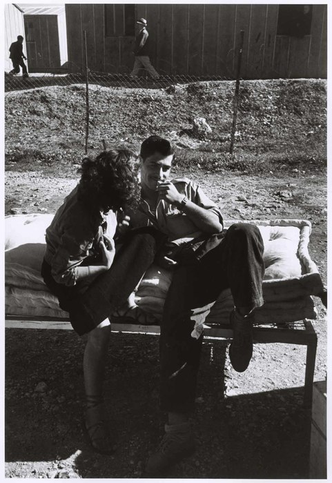 [Man and woman sitting on temporary beds outside, Haifa]