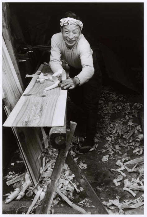 [A carpenter planes down a wooden plank by hand, Japan]
