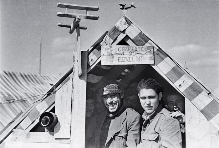 [Republican refugees standing under a sign saying "Gran-Hotel Euzkeldun no. 95" at an internment camp for Spanish exiles, Le Barcarès, France]