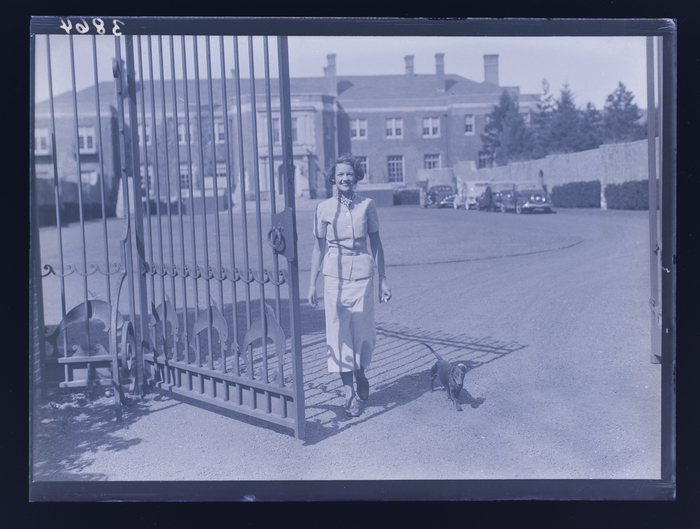 [Woman walking through gate with dachshund]