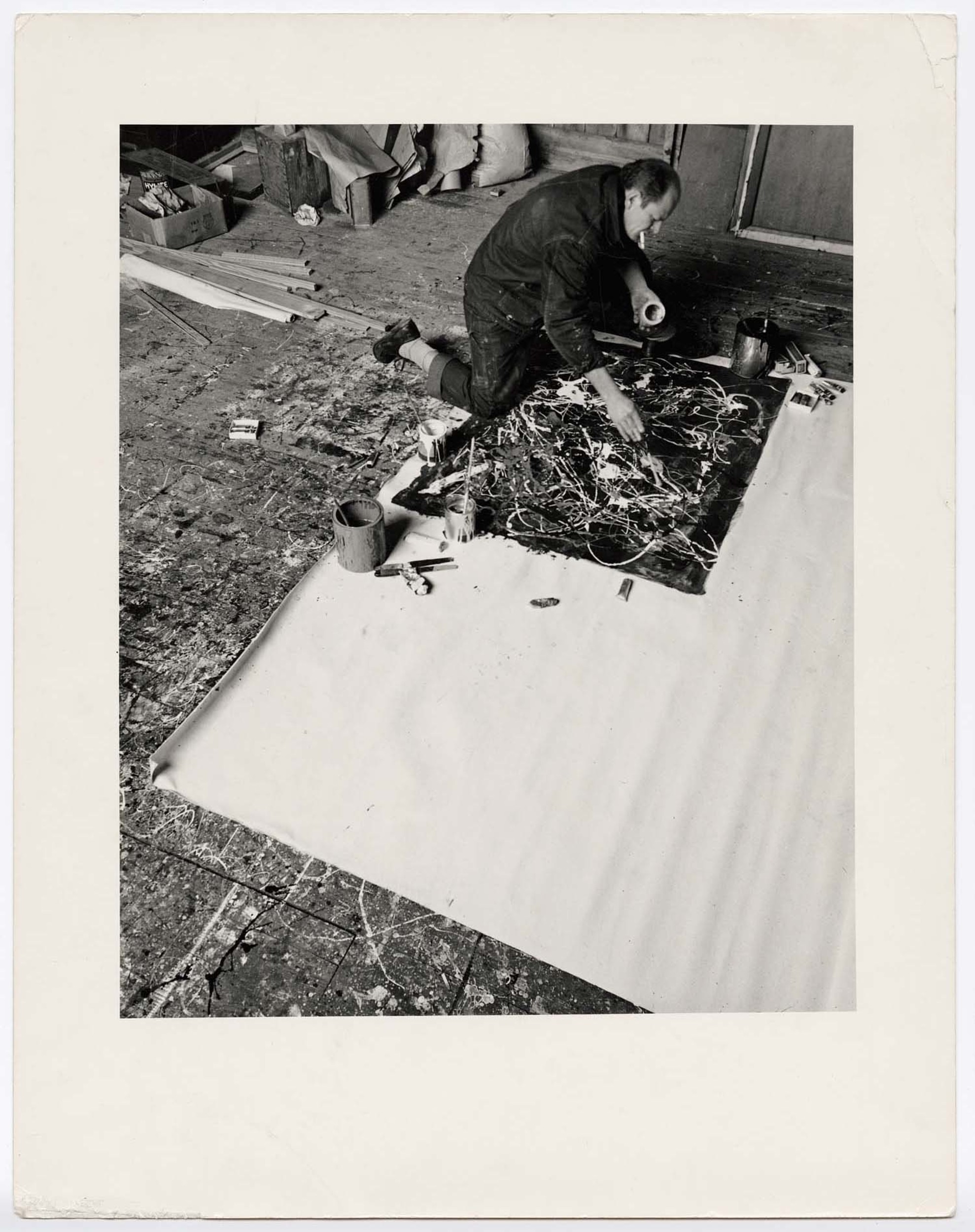 [Jackson Pollock kneeling on floor, working on a painting in his studio