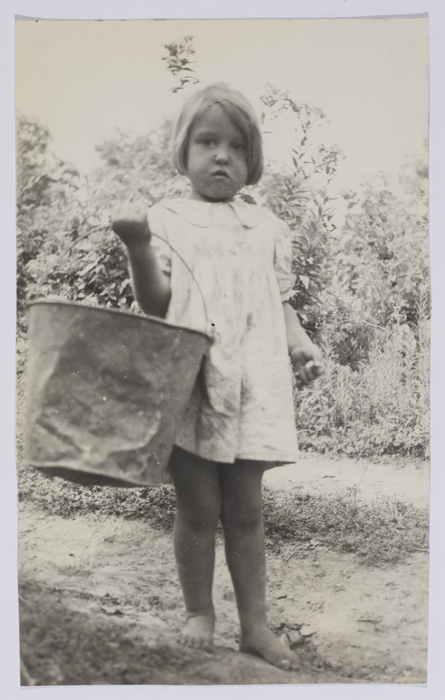 [Young girl holding pail on vegetable farm]