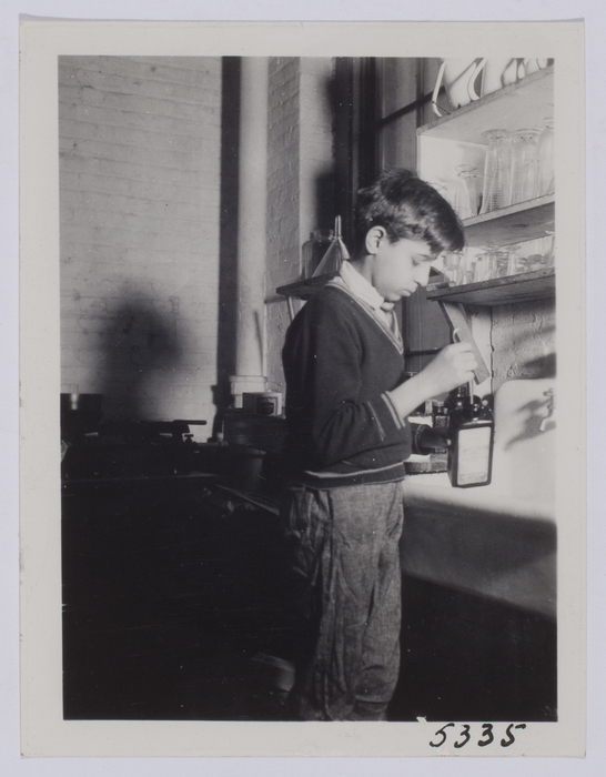 [Young boy standing with measuring beakers]