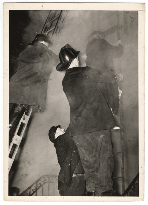 "Smoke swirling about them, these firemen help another woman down the ladder, while a third firefighter reaches up to help."