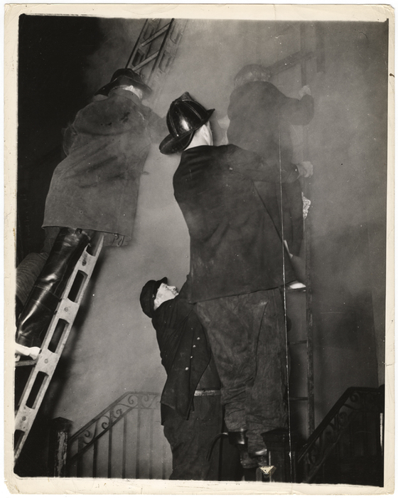 "Smoke swirling about them, these firemen help another woman down the ladder, while a third firefighter reaches up to help."