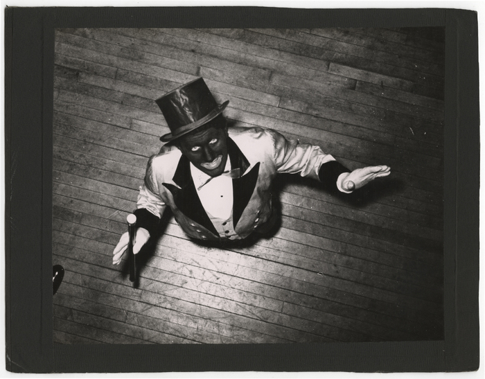 [man with blackface and top hat on stage]