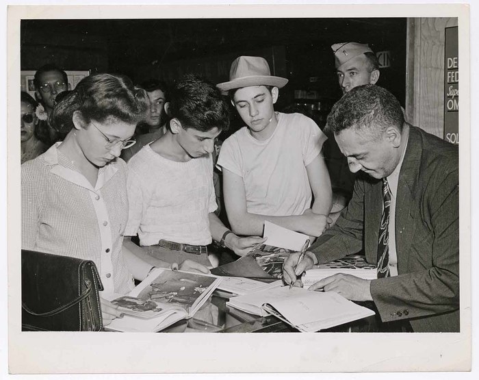 [Weegee signing copies of "Naked City"]