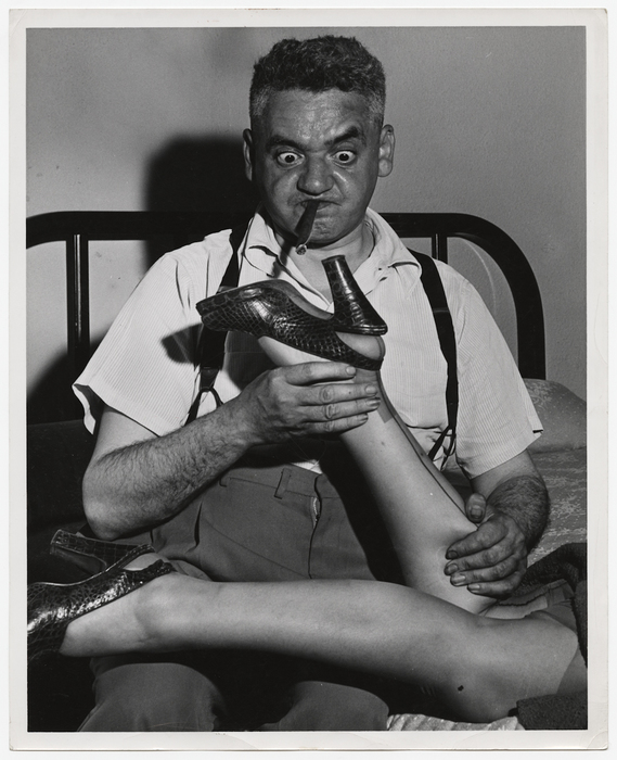 [Weegee holding woman's leg and ogling heel]