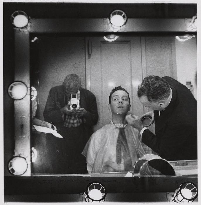 [Weegee photographing Art Ford in a mirror, having makeup applied]